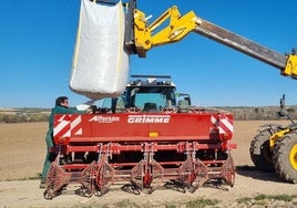 Un agricultor prepara la máquina para sembrar patatas.