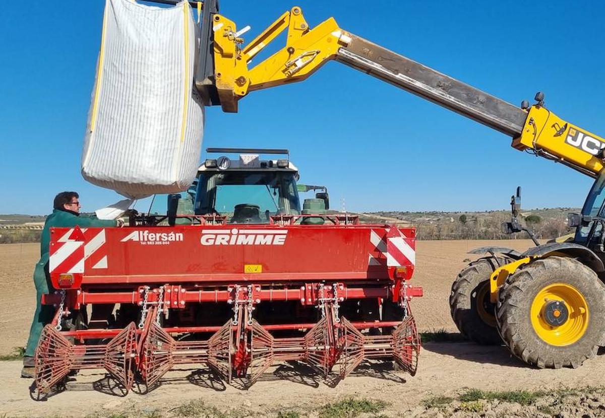 Un agricultor prepara la máquina para sembrar patatas.