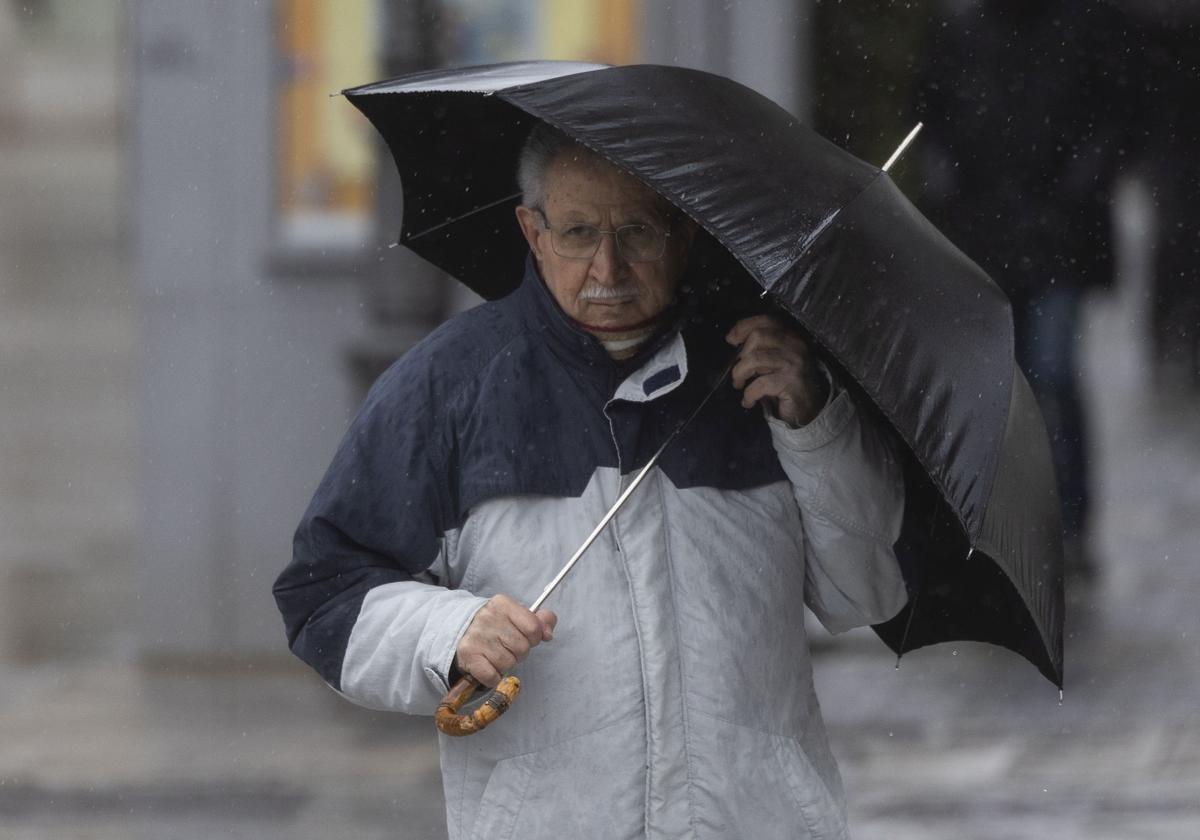 Un hombre se protege de la lluvia en Valladolid en una imagen de archivo.