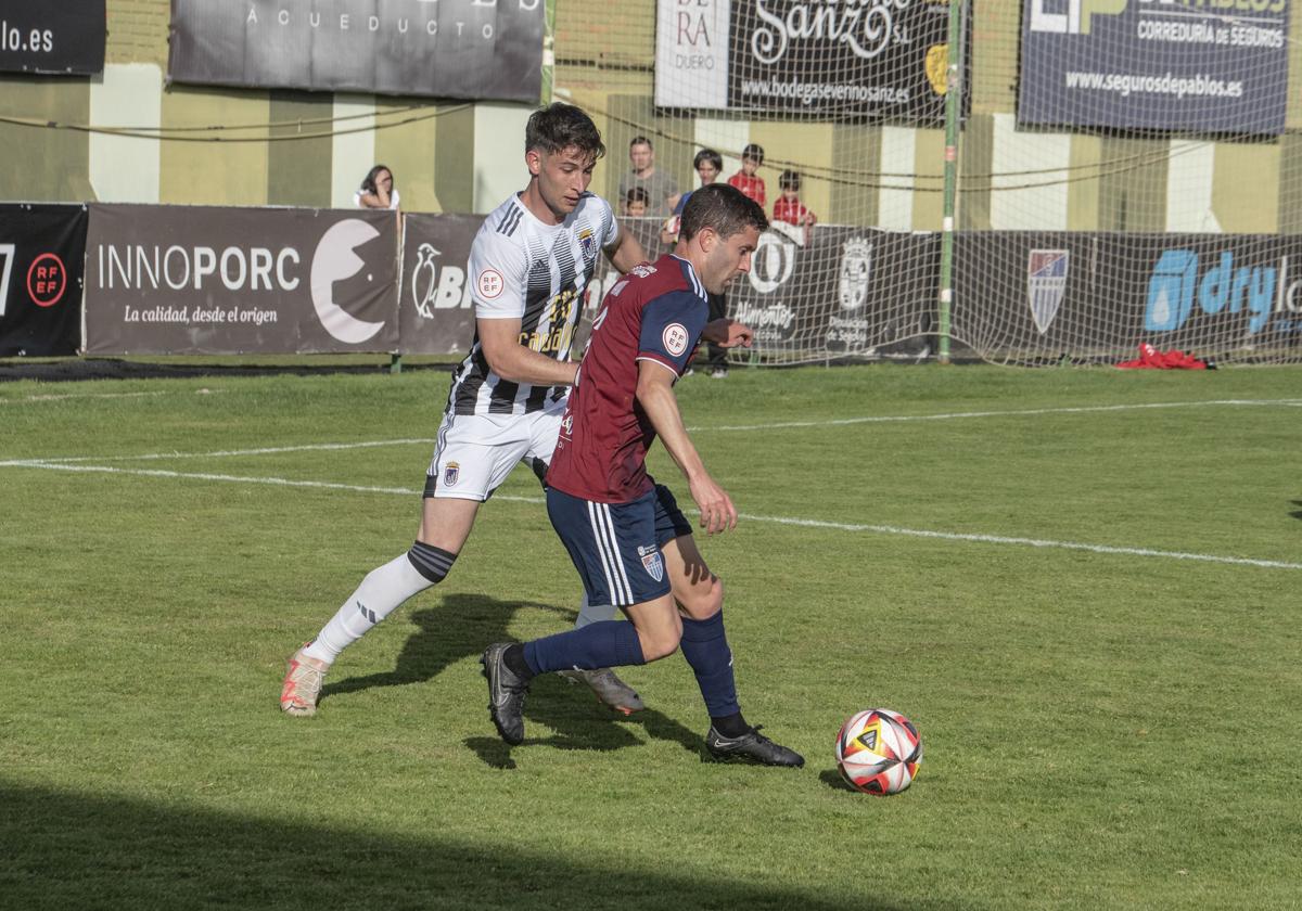 Manu conduce el balón presionado por un rival en un partido en La Albuera.