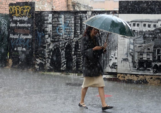 Una mujer se protege de la lluvia y el granizo con un paraguas, en la calle San Francisco.