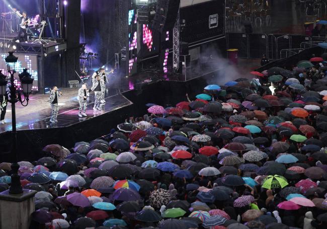 El público se protege con paraguas durante el concierto.