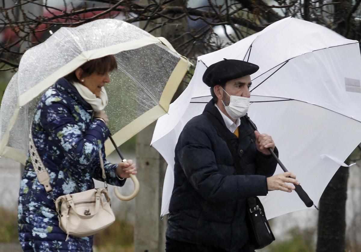 Dos transeúntes se protegen bajo sus paraguas de la lluvia en Segovia.