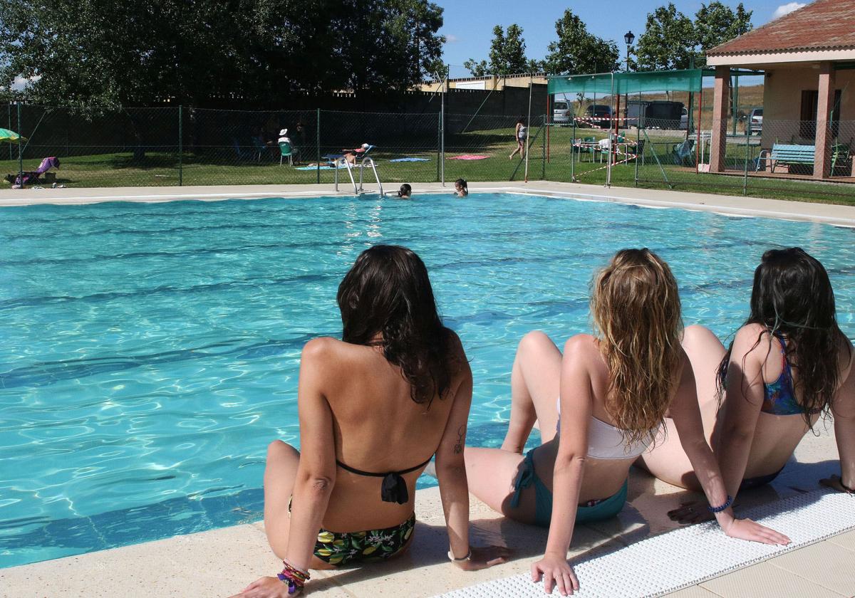 Unas jóvenes toman el sol en la orilla de la piscina de Palazuelos de Eresma.