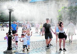 Mayores y pequeños se refrescan en un día de mucho calor.