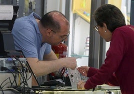 Un comerciante de la ciudad de Segovia enseña un producto a una clienta.