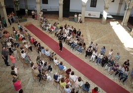 Una mujer desfila en el Palacio Episcopal ante la expectante mirada del público.