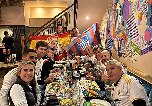 Fernando de Frutos, con la bandera de la Segoviana, junto a otros aficionados compartiendo comida en un restaurante español.