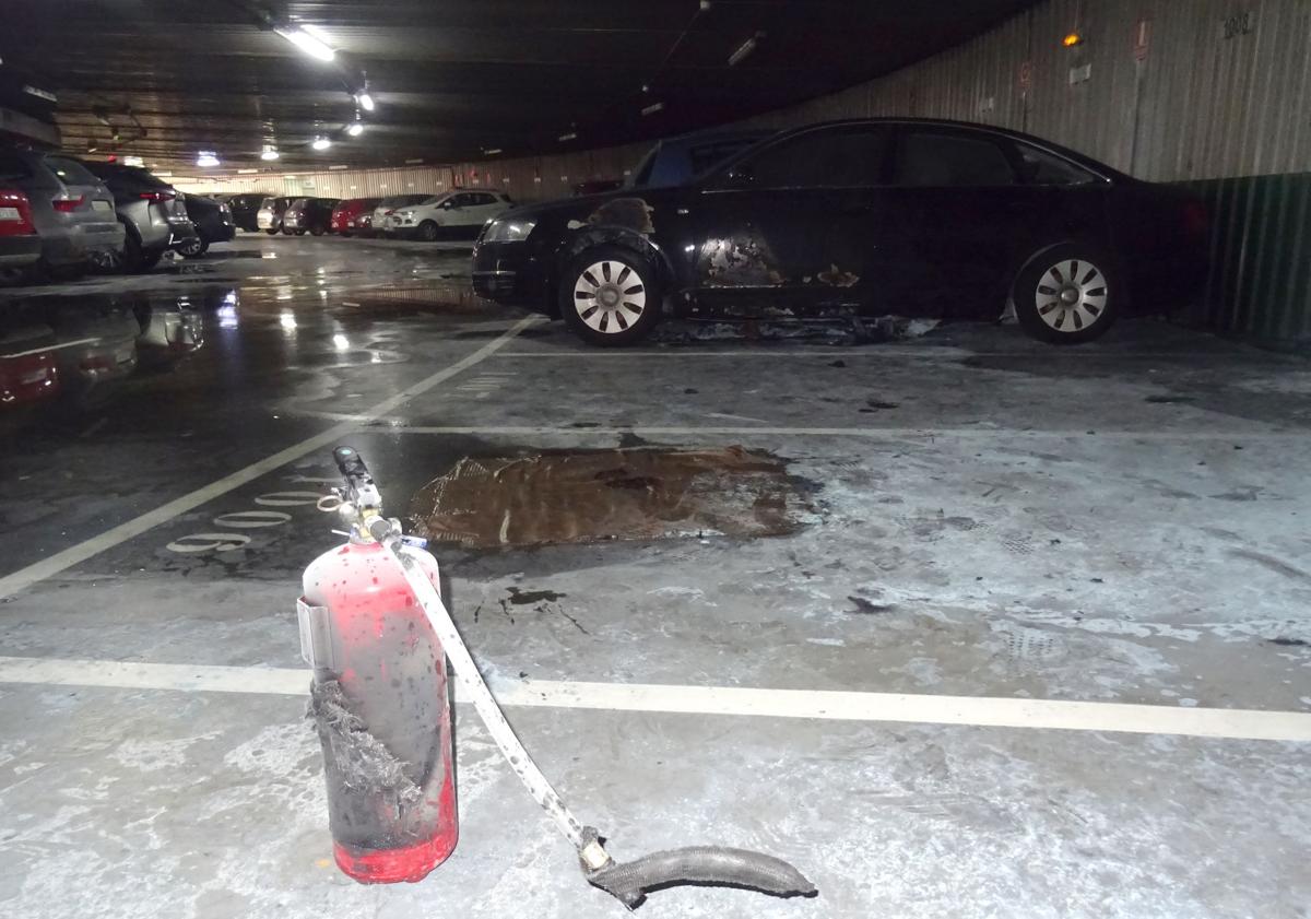 Imagen principal - Un extintor vaciado junto al coche afectado por el incendio y acceso al aparcamiento para residentes de la plaza de la Circular.