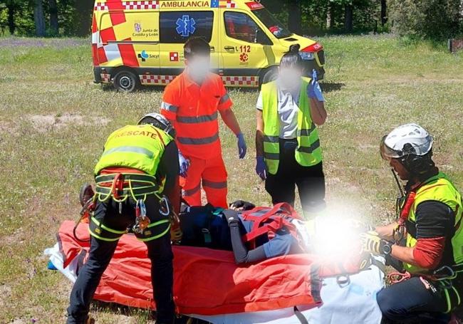 Los rescatadores de la Junta posan al herido en una explanada de La Granja antes de ser evacuado en ambulancia.