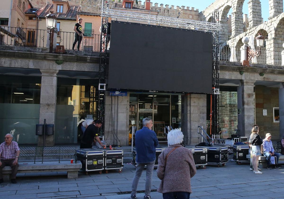 Unos transeúntes se quedan mirando la instalación de la pantalla gigante en el Azoguejo, este miércoles.