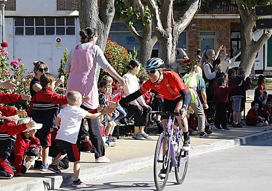 Una ciclista saluda a un niño tras comenzar la Vuelta Ciclista