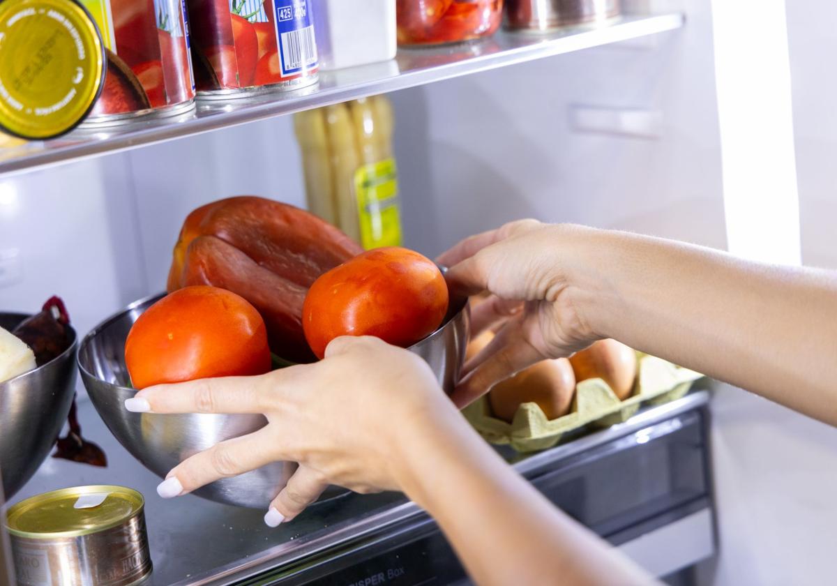 Una mujer coloca productos en un frigorífico.