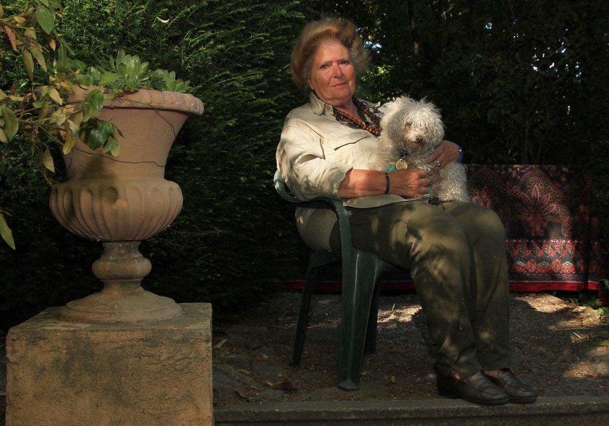 Julia Casaravilla, sentada en el jardín sujetando a su perro.