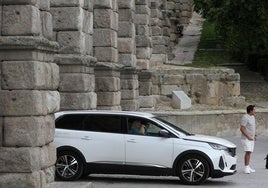 Un coche conducido por un extranjero cruza bajo los arcos del Acueducto este martes.