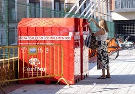 Una mujer deposita ropa en uno de los contenedores de Cáritas.