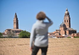 Una mujer observa las dos iglesias de Alaejos.