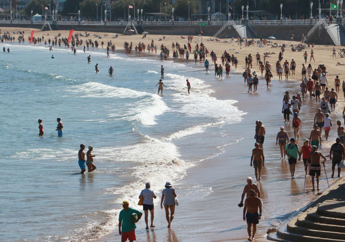 Gente paseando y tomando el sol en la playa, en imagen de archivo.