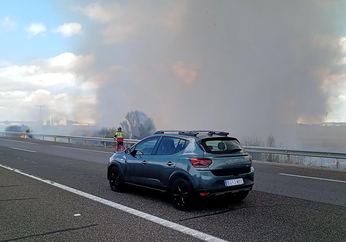 Un bombero participa en la extinción del fuego junto a la autovía A-65.