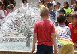 Unos niños juegan junto a una fuente en Palazuelos de Eresma.