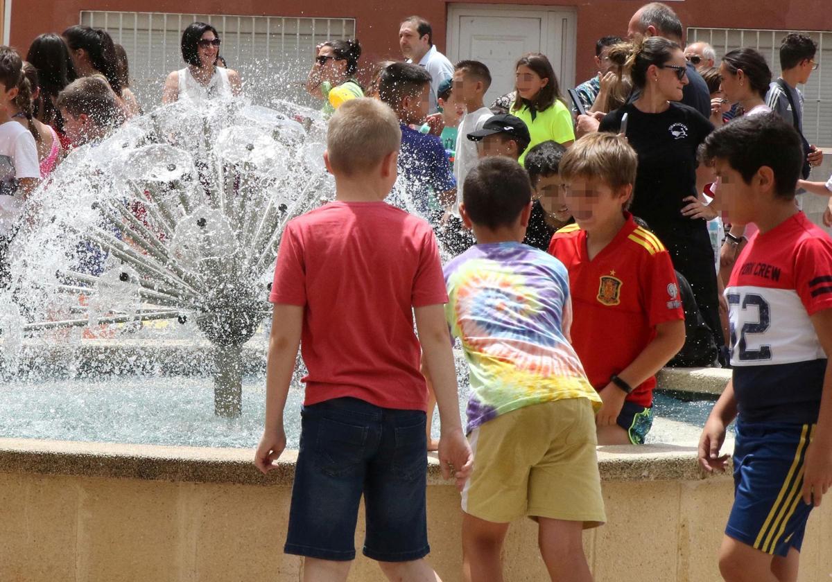 Unos niños juegan junto a una fuente en Palazuelos de Eresma.