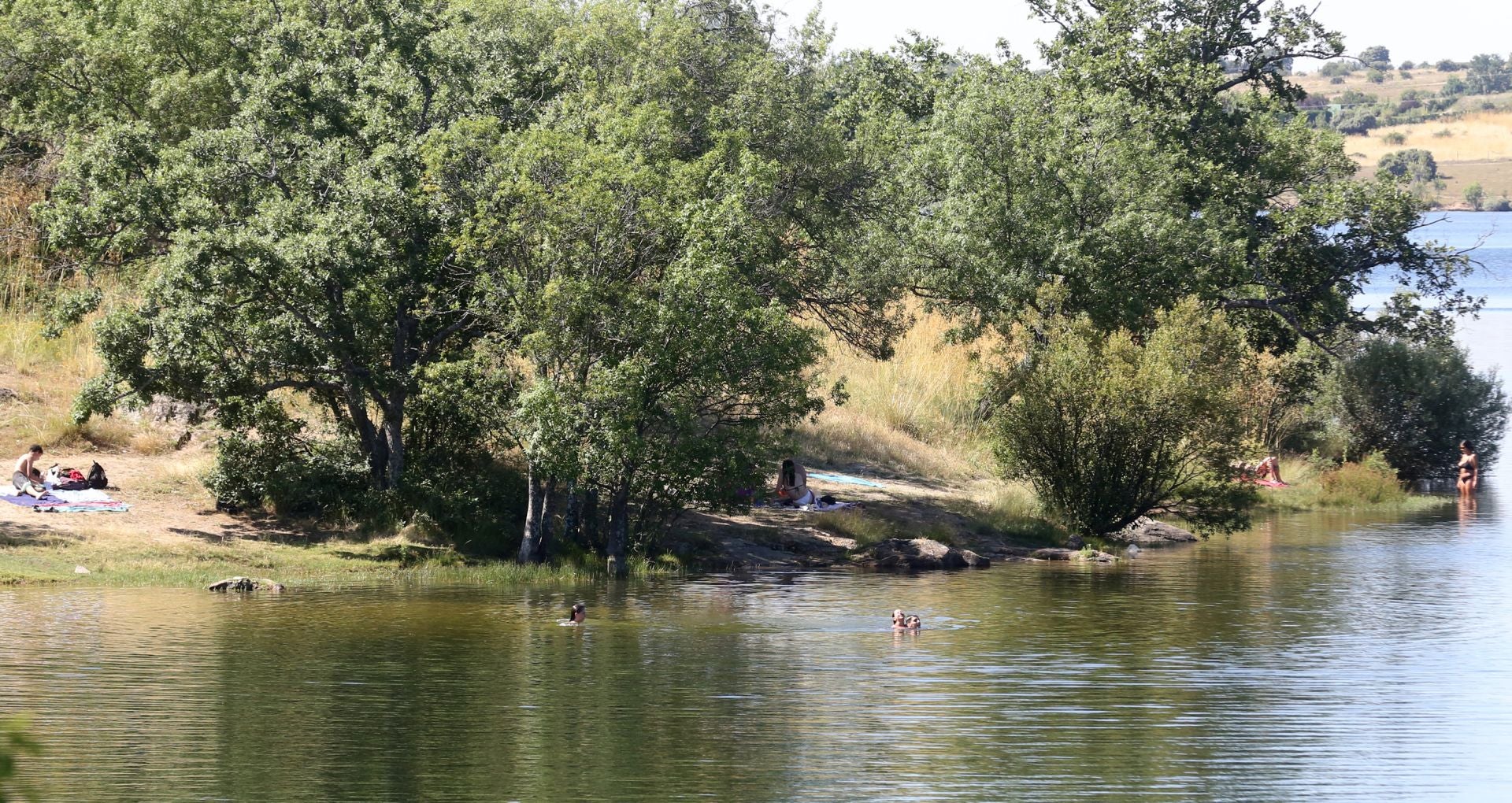 Varias personas se bañan en el Pontón mientras un par de grupos toma el sol en la orilla.