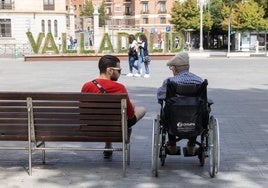 Un joven con una persona mayor en silla de ruedas en Valladolid.