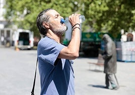 Un hombre lucha contra el calor hidratándose.