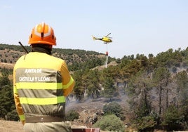 Un helicóptero descarga agua sobre el incendio ante la mirada de un agente de la Junta.