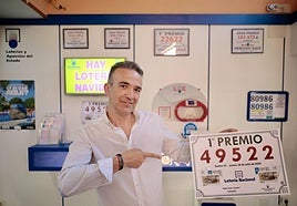 David Arteaga, propietario de la Administración, junto al cartel con el número del primer premio de la Lotería Nacional.