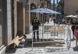 Un trabajador se protege del sol con una sombrilla en la Calle Real de Segovia, este martes.