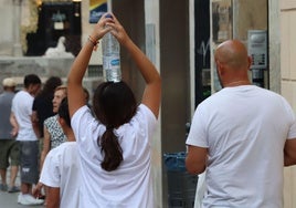 Una chica lleva una botella de agua sobre la cabeza para aliviar el calor de este lunes.