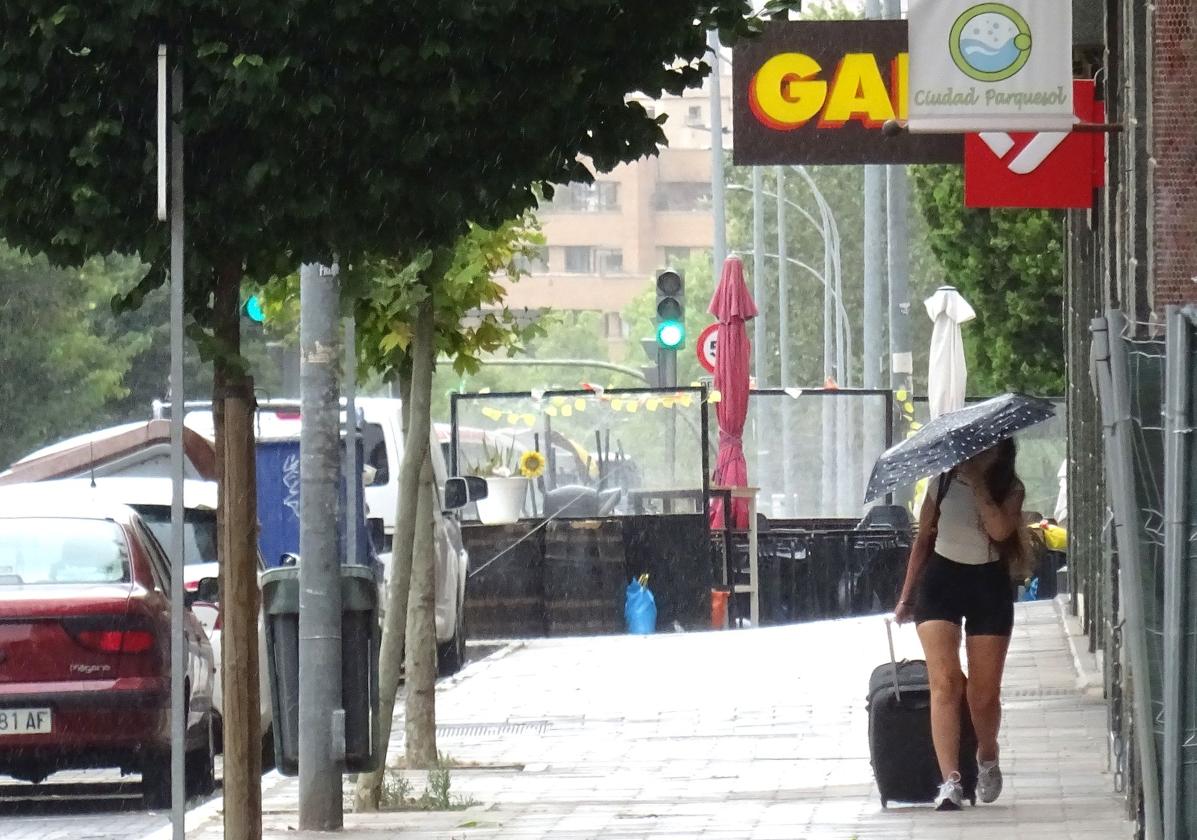 Una joven se protege del chaparrón en Parquesol.