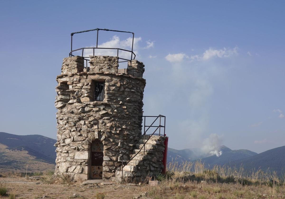 Torre de Cabeza Reina, este jueves sin vigilancia presencial, y al fondo el humo del incendio en la garganta del río Moros.