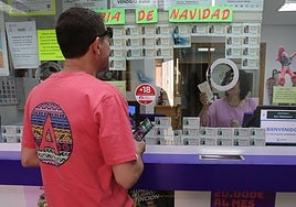 Una lotera atiende a un hombre en una administración de la capital.