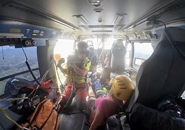 Una rescatista da indicaciones a la mujer herida tras ser evacuada en helicóptero.