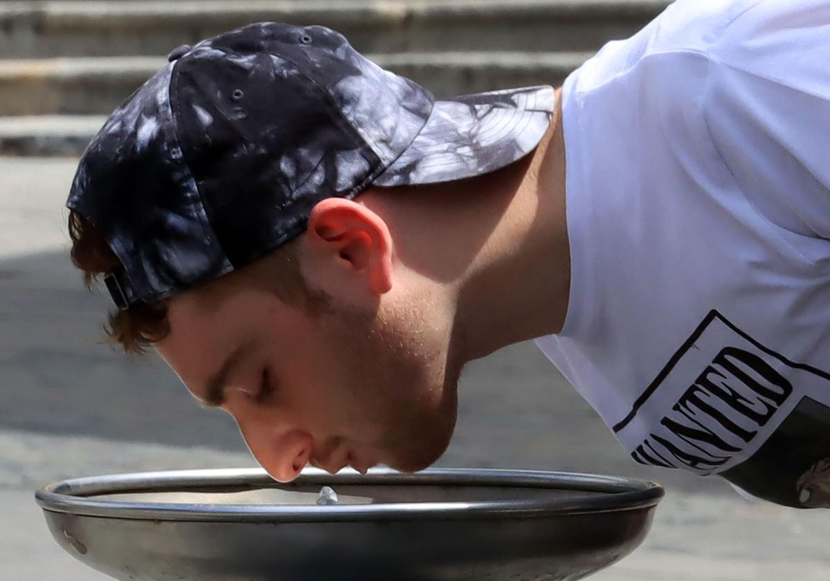 Un joven bebe agua para hidratarse en una fuente durante estos días de calor en Segovia.