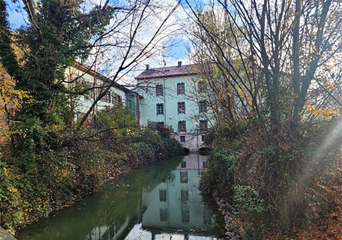 Imagen principal - Foto 1: La fachada trasera de la fábrica La Perla, con la entrada del derrame del canal para suministro de fuerza motriz. Foto 2: Compuerta del canal y apoyo de los postes de sujeción de las barcas, visibles durante las obras de limpieza de la dársena realizadas en 2023. Foto 3: Imagen actual de la dársena del canal. 