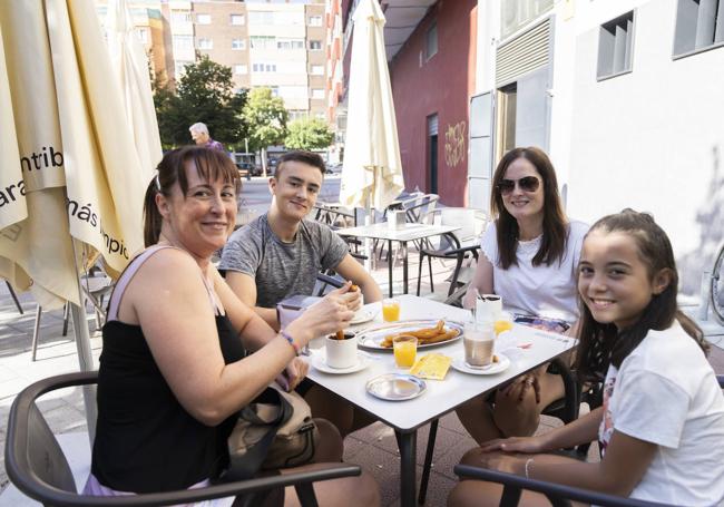 Vecinos de Valladolid desayunan chocolate con churros en una terraza.