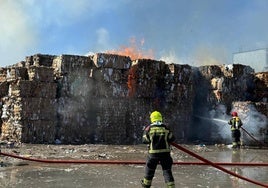 Los bomberos trabajan en la extinción de las llamas en las grandes pilas de celulosa.