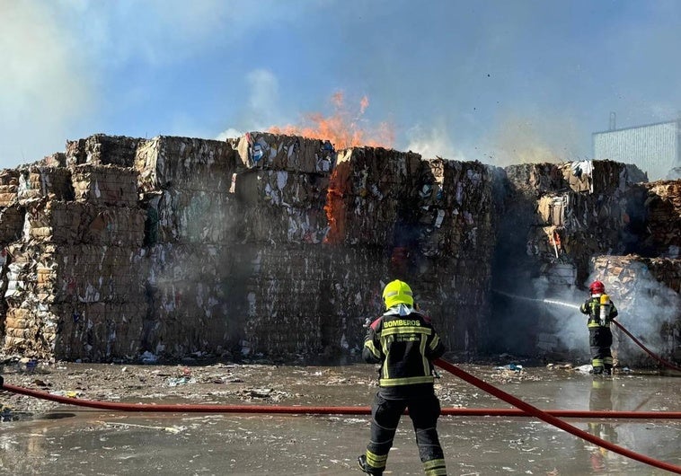 Los bomberos trabajan en la extinción de las llamas en las grandes pilas de celulosa.