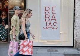 Una pareja de jóvenes con bolsas en la calle Santiago de Valladolid al inicio de las rebajas de verano de este año.