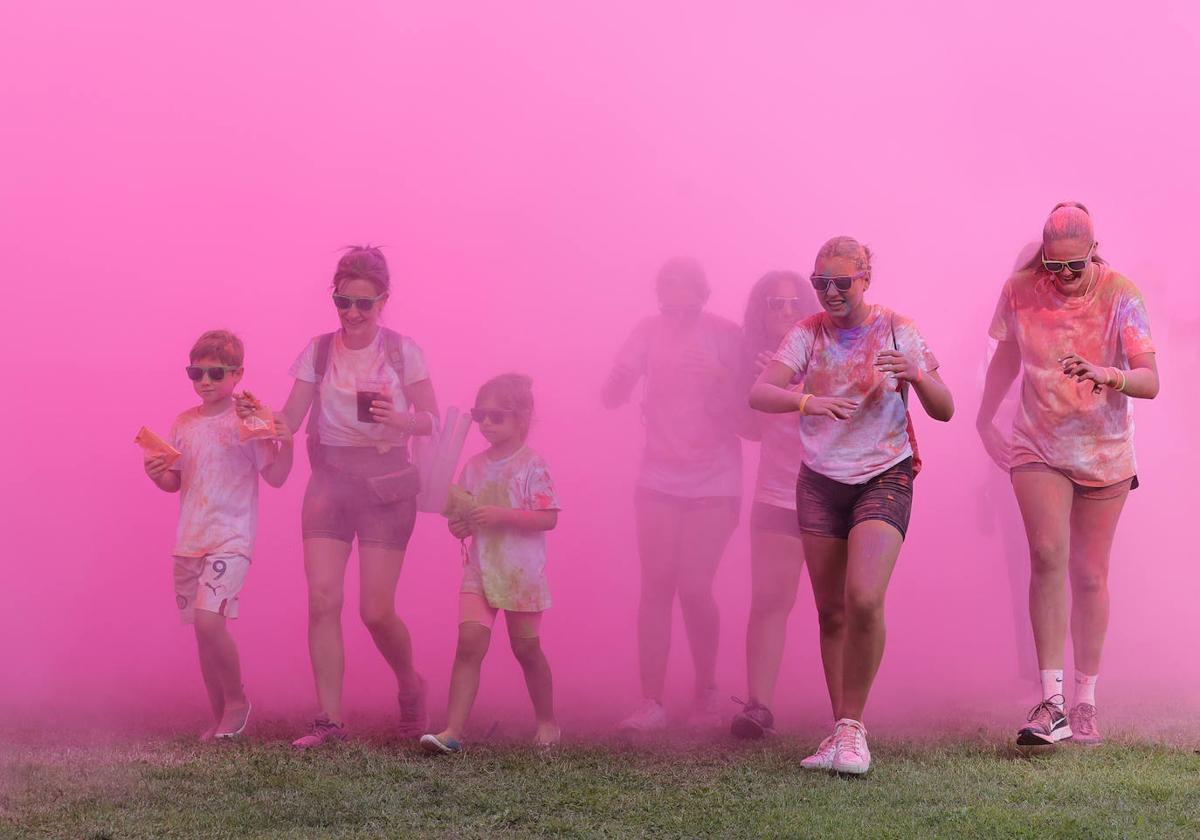 Participantes en la Holi atraviesan la nube morada de salida.