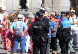 Agentes policiales vigilan a un grupo de turistas para evitar carteristas en la ciudad.