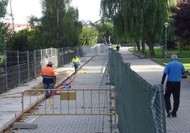 Los operarios introducen las canalizaciones para las farolas al borde de la plataforma del carril bici.