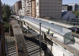 Los operarios trabajan sobre el vano que se sitúa sobre las vías del ferrocarril.