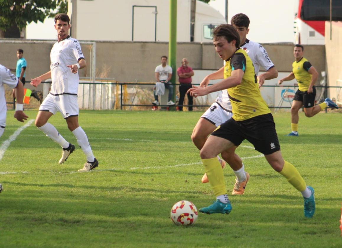 Alfonso progresa con el balón controlado perseguido por un rival del Júpiter, este domingo en Mojados.