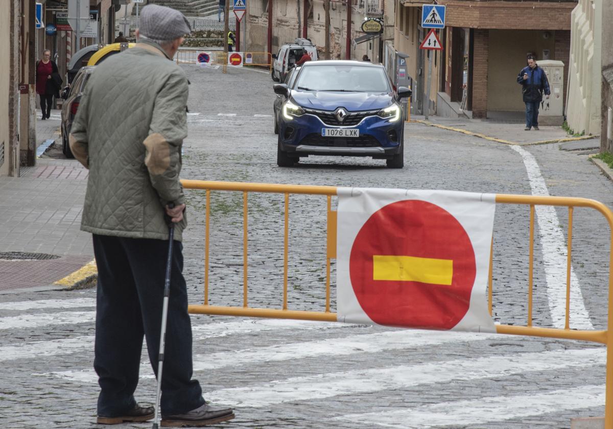 Un hombre pasea junto a una valla por la realización de obras en Segovia capital.