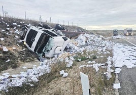 Uno de los camiones volcados en el arcén tras la colisión.