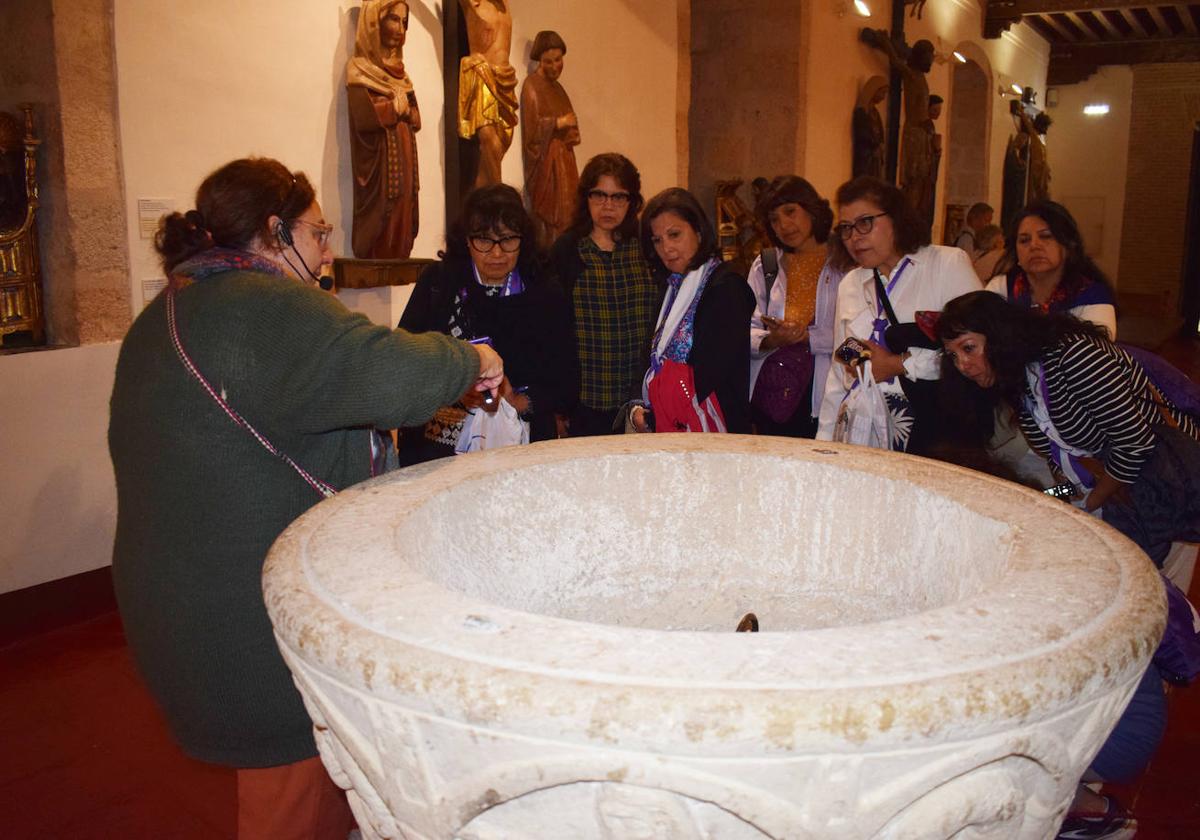 La guía del Museo Diocesano Isabel Reyes enseña a un grupo de americanos la pila bautismal de Valcobero.